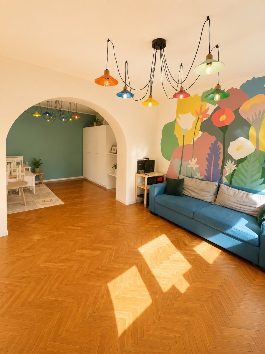 Sala mare a centrului: mural cu flori pictat pe perete, canapea albastră, parchet și arcadă spre sala de grup