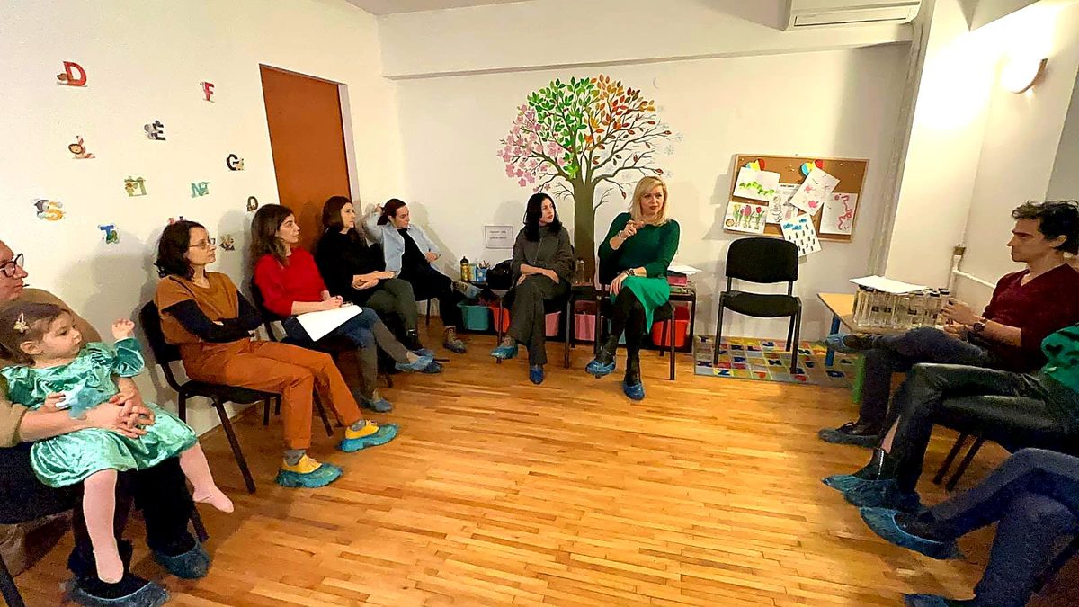 Raluca Tita și părinți așezați în cerc, într-o sală de grădiniță, la workshopul despre adaptare