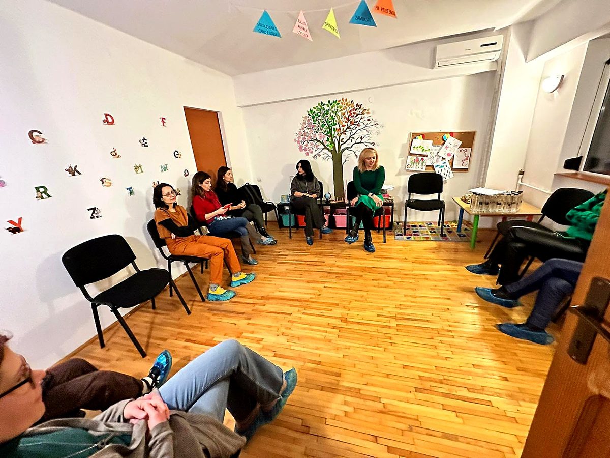 Grup de părinți în cerc, ascultând, la workshopul despre primii pași spre grădiniță