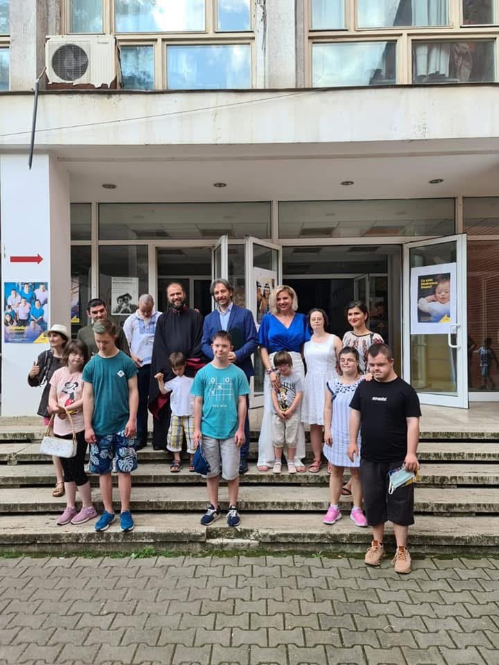 Fotografie de grup cu copiii, părinții și specialiștii prezenți la eveniment, pe treptele centrului cultural